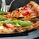 Pizza napolitana con tomates cherry, pepperoni, pimientos, queso y albahaca